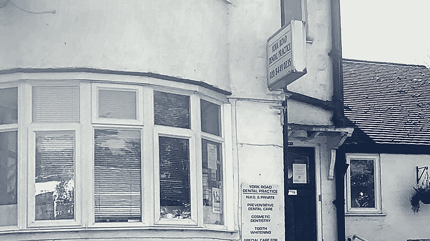 The practice's curved bay window, with the hanging sign above the door.